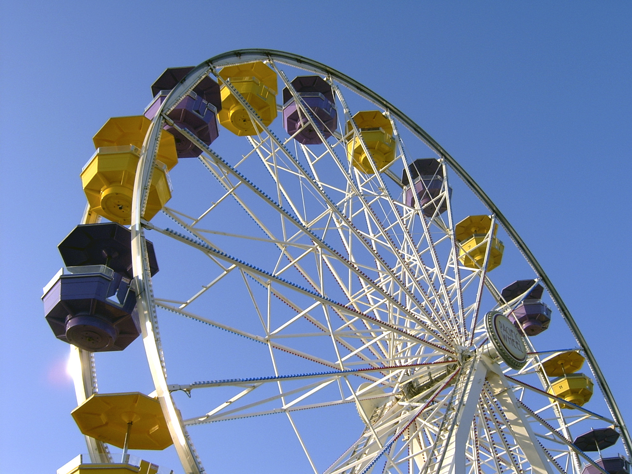 interesting perspective shot of a ferris wheel against a clear blue sky.